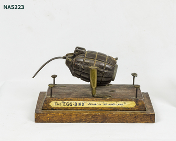 WWI French Art consisting of hand grenade "bird" mounted on wooden base cartridges as pivot surrounded by 4 British Buttons. 