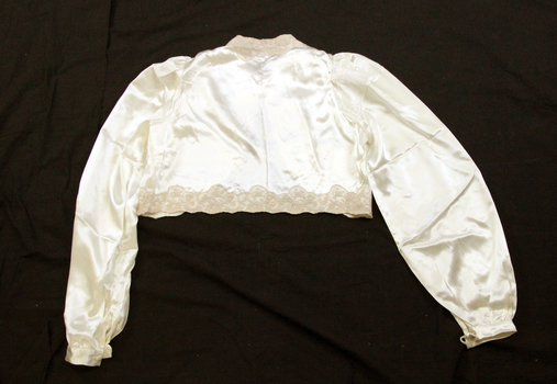 Bedjacket is short with long sleeves (back). Coffee coloured. 