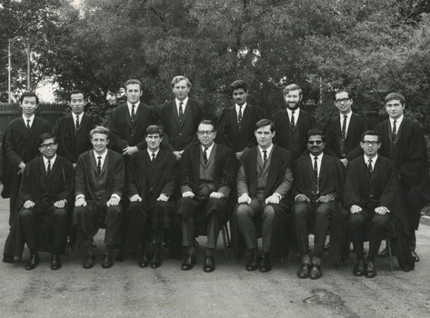 Black and white photographs showing fourteen male tutors of International House and the Warden of International House Sam Dimmick dressed in suits and academic gowns. 