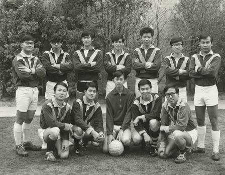 Black and white photograph showing twelve male residents of International House, seven standing with their arms crossed and five squatting, dressed in their soccer kit.