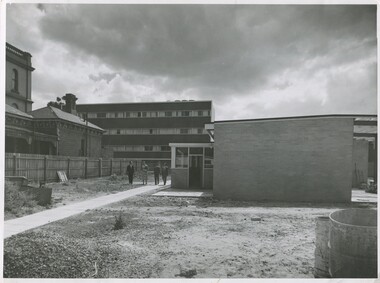 Four people (three men and one woman) walking near the recently completed Ian Clunies Ross Wing at International House.