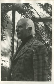 An older man wearing a tartin blazer and black turtle neck. 
