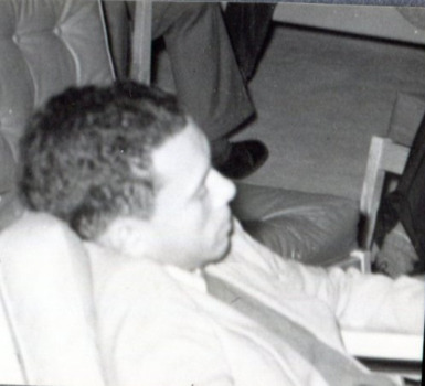 Young man in a suit with close, curly hair sleeps in an armchair