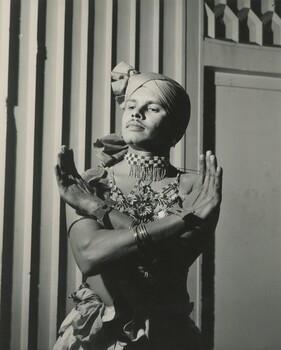 A male in traditional South Asian dance attire posing for a picture. 