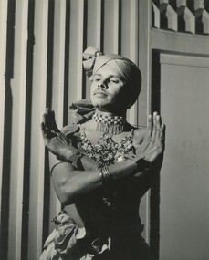 A male in traditional South Asian dance attire posing for a picture. 