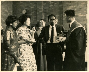 From the left, a woman in a Sari, a woman in a floral print dress, a man in a suit with his hands on his hips (Rajaratnam Sundarason), a man side-on to the camera looking away from the camera to Rajaratnam in a suit and Oxford robe. 