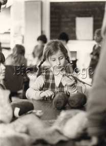 Photograph - Student sitting in a classroom and knitting, c. 1980s