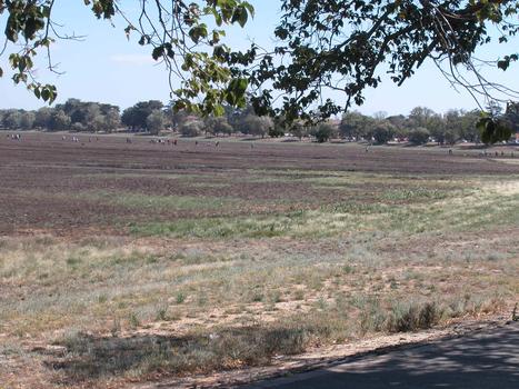 A number of people walk through a dry creek bed