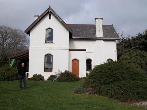 A man stands beside a double storey house