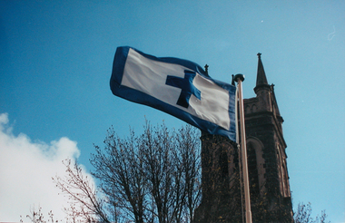 A white flag with blue edge and cross blows in the wind
