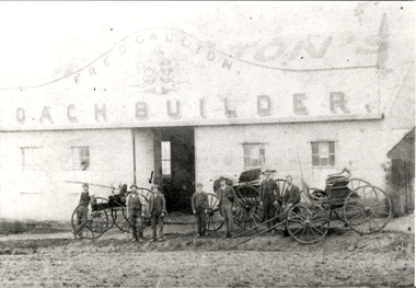 Six men pose with 3 carriages in front of a building