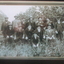 Thirteen men in hats sit for a group photograph