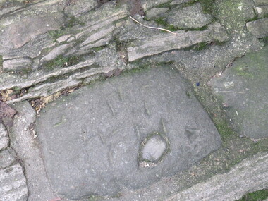 Flagstone has masons marks or identifying marks on it.