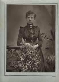 A woman stands in front of a vase of flowers
