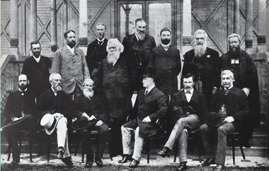 Fourteen men stand and sit