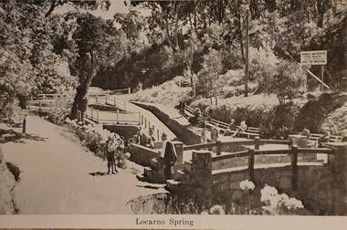 A stone bridge is situated in the foreground, with Locarno Spring in the background