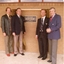 Four men outside a plaque