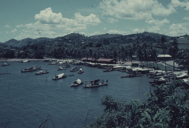 Boats on the harbour at Koki with the market buildings in the background with the red roofs.