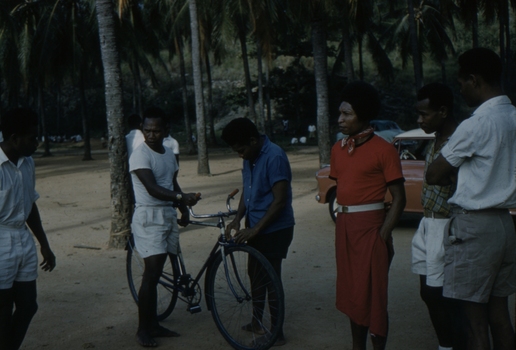 Papuans at Koki, Port Moresby. A push bike is being admired.