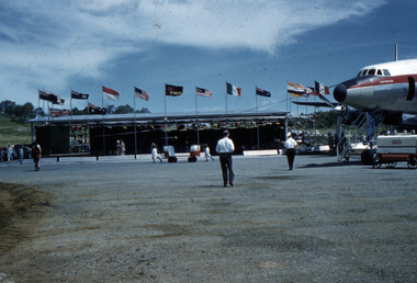 Port Moresby Qantas terminal showing flags from other nations and tarmac. Alec Kinnane was one of the engineers who worked on this airstrip.