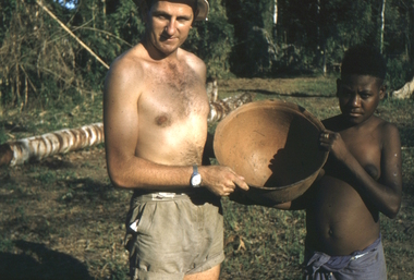 A Papuan boy and man showing the photographer a large bowl.