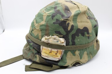 Equipment - Vietnam Helmet with camouflage cover, Camel cigarettes in outside band