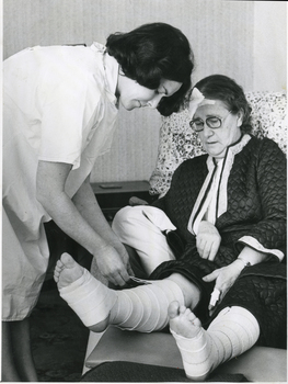 A Sister of the Royal District Nursing Service administering wound care to a lady in her home
