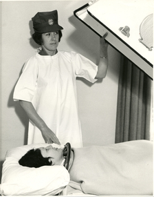 A Melbourne District Nursing Service (MDNS) Sister attending a lady in a Negative Pressure Ventilator 