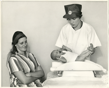 A Royal District Nursing Service (RDNS) Sister weighing a baby