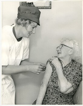 A Melbourne District Nursing Service (MDNS) Sister administering an injection to an elderly lady