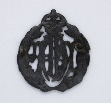 Back of blackened brass badge with crown on top and leaf crest either side of the letters RAAF in centre. Single brass fastening loops on left and right.