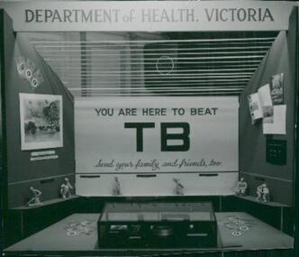 Photograph, A photo of a poster headline "You are here to beat TB", and "Send your family, and friends, too" taken of a promotional display at the Department of Health chest x-ray clinic, Tuberculosis Branch. The photo is from a photograph album circa 1962, c 1962