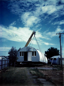 Photograph, Photo of a crane - off an International truck - hoisting and assisting in the removal / installation of an original World War II era Nissen Hut from Sandhurst Training Centre - Circa 1973