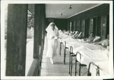 Photograph, A nurse walks past tuberculosis (TB) patients who are resting in beds in the open air of a sheltered verandah, circa 1932, at Gresswell Sanitorium - Mont Park