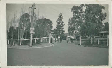 Photograph, Patients, staff and visitors, including a small child, congregated, and walking, near the entrance to Gresswell Sanitorium (spelt Sanatorium on the sign post), where tuberculosis is treated, circa June 1946 - Mont Park