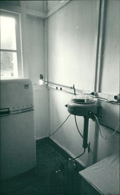 Photograph, “For 30 minutes (sometimes 120 minutes) a day, water runs through a hole in the wall into this modern aqua destilata machine". Equipment donated through Dr John A Forbes Fairfield / Gull Force 2/21 Bn AIF / Ziarah Caltex to Rumah Sakit Ambon Hospital Indonesia - Dr John Forbes photo albums of Ambon Hospital Indonesia Circa 1970 to 1971