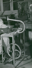 Photograph, A polio & tuberculosis (TB) patient using a scroll or band saw to cut intricate wooden designs as part of undertaking occupational therapy & recreational workshop activities
