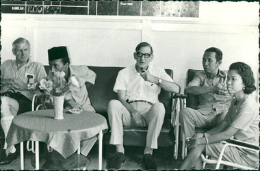 Photograph, Officials and medical staff and Australian contingent in informal discussions & settings inside the Hospital, Dr Forbes, with pipe, 3rd from right - Dr John A Forbes Fairfield / Gull Force 2/21 Bn AIF / Ziarah Caltex & Rumah Sakit Ambon Hospital - Photo is from Dr John Forbes photo albums - 1971