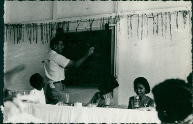 Photograph, Officials, medical staff and Australian contingent applying chalk to the blackboard - Dr John A Forbes Fairfield / Gull Force 2/21 Bn AIF / Ziarah Caltex & Rumah Sakit Ambon Hospital - Photo is from Dr John Forbes photo albums - 1971
