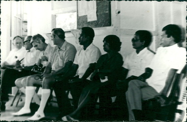 Photograph, Officials and medical staff and Australian contingent seated in a Hospital corridor - Dr John A Forbes Fairfield / Gull Force 2/21 Bn AIF / Ziarah Caltex & Rumah Sakit Ambon Hospital - Photo is from Dr John Forbes photo albums - 1971
