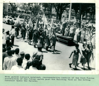 Girl Guides Association of the Colony marching past the saluting base and the Acting Governor of the British West Indies - Department of Health – National Fitness Office (Sports & Recreation) – Press Release Photo - Empire Youth Day & Royal Tours