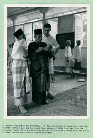 A Malaysian Kampong (Village) honours its new headman (Penghulu) Mohamed Noor, and Inche Talib, together with a British official Mr Foulsham - 2 of 2 photos - Department of Health – National Fitness Office (Sports & Recreation) – Historical Press Release Photo Collection