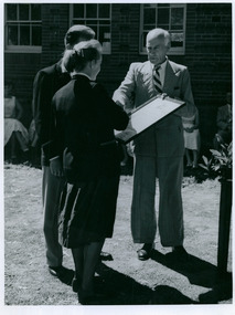 A dignitary handing the pledge - A Message of Loyalty to Queen Elizabeth II - to 2 high school students from Northam High School in Western Australia on 04/05/1958 - 1 of 3 photos - Department of Health – National Fitness Office (Sports & Recreation) – Historical Press Release Photo Collection