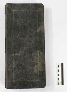 Front cover of a Kalamazoo visible card book used for accounting in the J. Mann & Sons General Store in Wodonga, Victoria. Black and white 10 cm scale to one side.