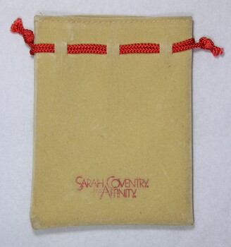 Front of a small faux suede jewellery pouch with a red draw string with the names "Sarah Coventry" and "Affinity".