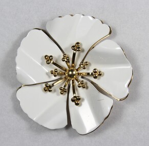 Front of a white and gold-toned metal brooch in the shape of a flower from the Sarah Coventry Pty. Ltd. jewellery range.