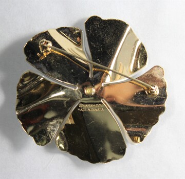 Back of a white and gold-toned brooch in the shape of a flower from the Sarah Coventry Pty. Ltd. jewellery range.