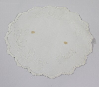 Haeusler Collection Embroidered white doily with the word cake and a floral pattern embroidered on the surface 