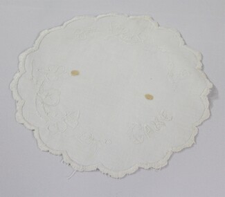Haeusler Collection Embroidered white doily with the word cake and a floral pattern embroidered on the surface 