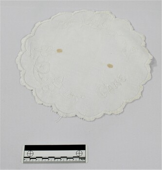 Haeusler Collection Embroidered white doily with the word cake and a floral pattern embroidered on the surface 